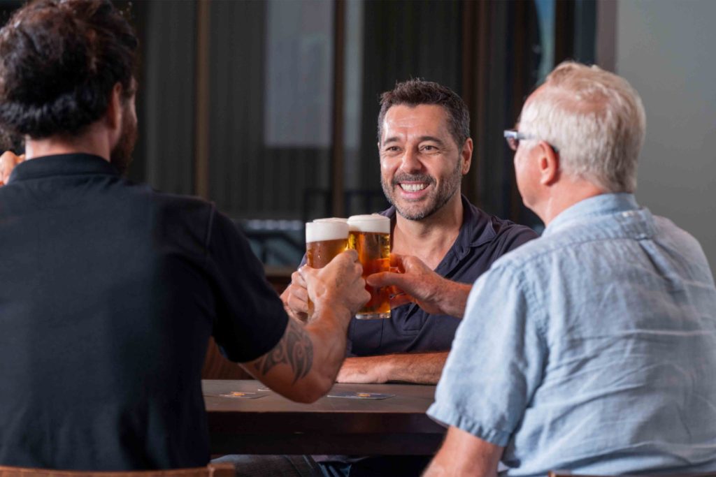 Two men standing at a bar holding drinks