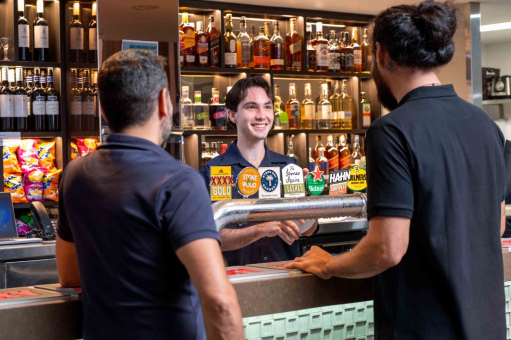 Two men standing at a bar talking to a Brothers Leagues Club staff member
