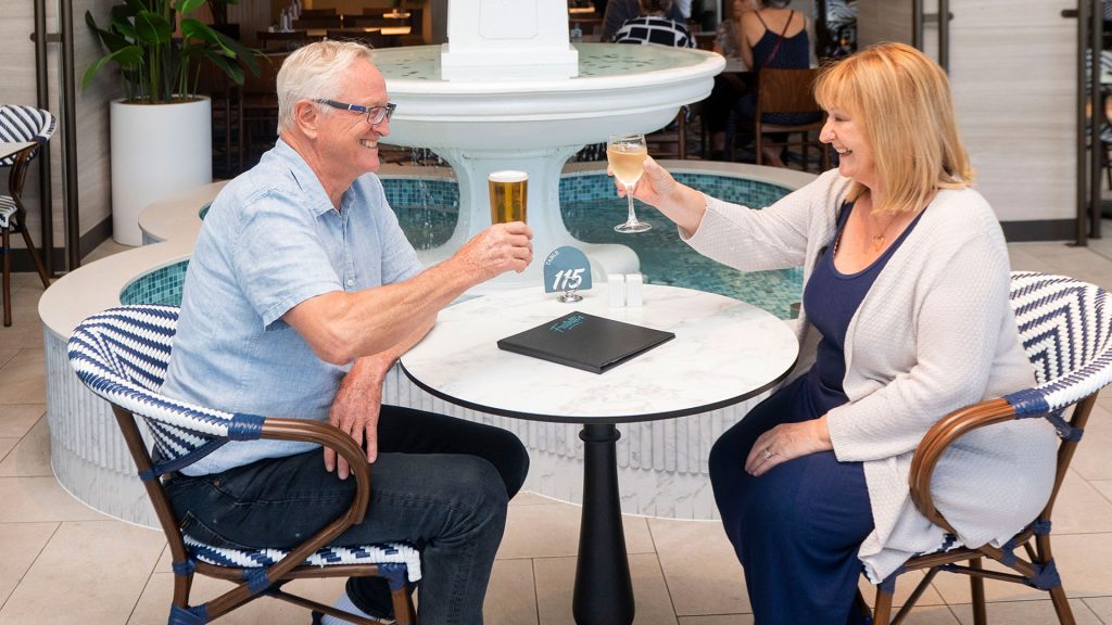 Two people seated at a table with drinks and menus Fratelli’s restaurant